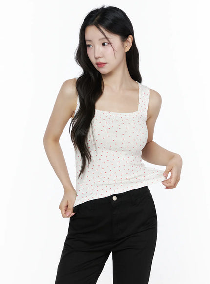 Heart Polka Dot Tank Top IU525 White front three-quarter view on model pulling hem to show stretch, highlighting red heart scattered pattern and ribbed fabric