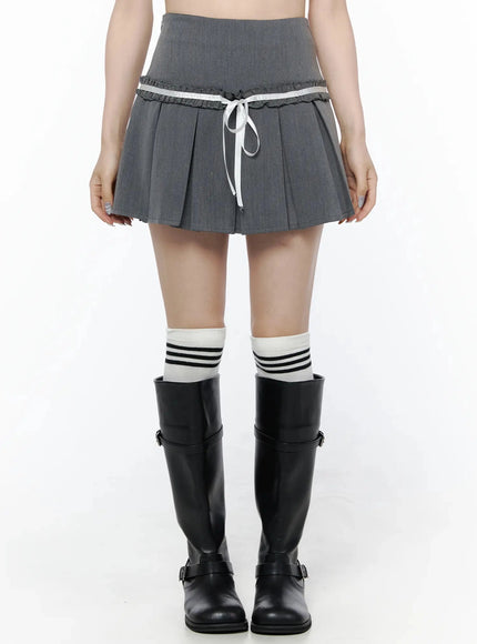 LEWKIN High-Waist Bow Pleated Skirt IL506 Dark gray front view on model wearing black knee-high boots and striped socks, white ribbon bow detail