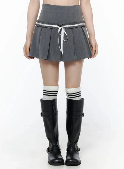 LEWKIN High-Waist Bow Pleated Skirt IL506 Dark gray front view on model wearing black knee-high boots and striped socks, white ribbon bow detail