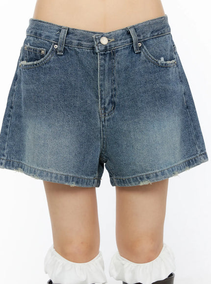 High-Waist Denim Jorts CU530 Dark blue close-up front detail shot on model showing washed denim texture, front pockets, and frayed raw hem