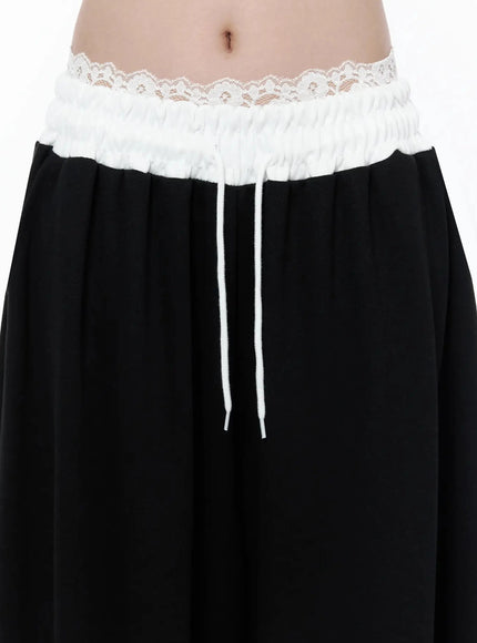 High-Waist Lace Wide Leg Sweatpants IL506 Black close-up detail shot of white lace trim smocked waistband and white drawstring on model