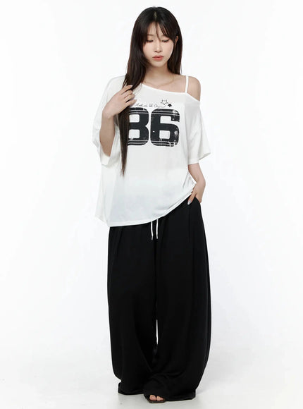 High-Waist Lace Wide Leg Sweatpants IL506 Black full-body front model shot with white 86 graphic tee eyes downcast hand in hair relaxed standing pose