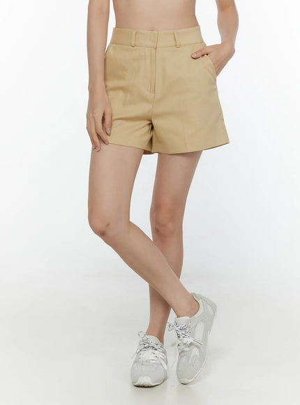 LEWKIN High-Waist Pintuck Shorts CL520 beige three-quarter front shot on model with hand in pocket styled with white sneakers