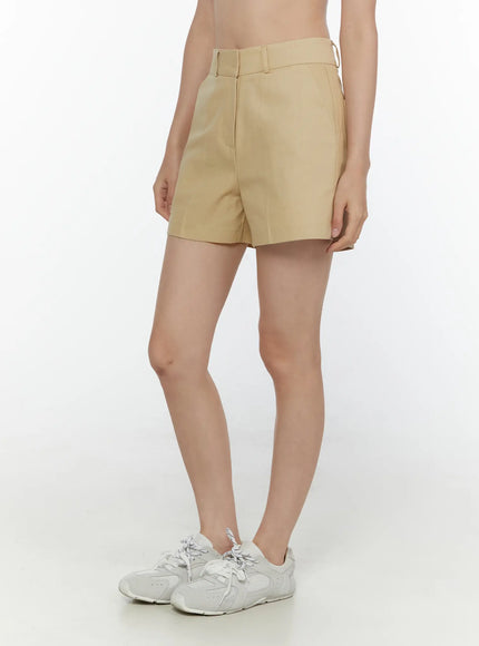 High-Waist Pintuck Shorts CL520 beige side shot on model showing waistband and clean side seam with white sneakers