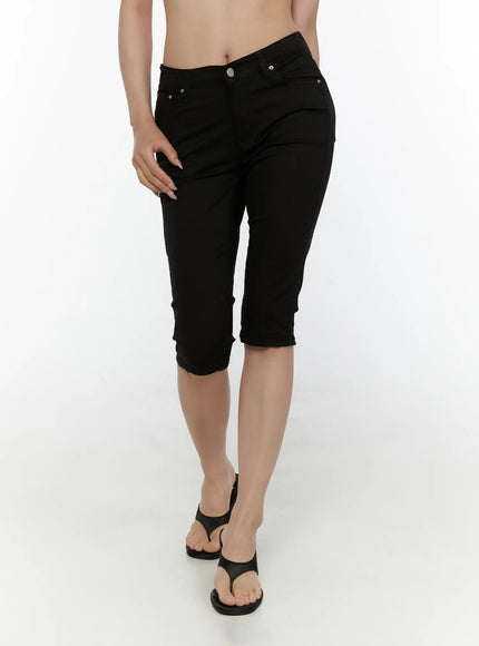 Hip-Pad Capri Pants CL507 Black front view on model showing low-rise waistband silver button coin pocket slim leg and raw cuffed hem with wedge sandals
