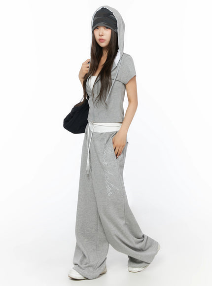 Hooded Short Sleeve Zip-Up IL515 Gray three-quarter front view on model with hood up cap underneath carrying black bag walking pose