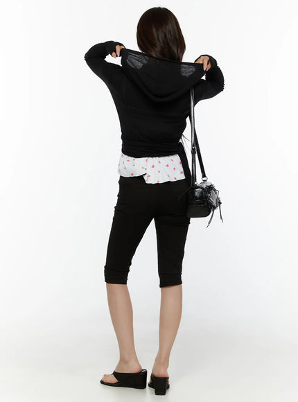 Hooded Wrap Crop Cardigan CL507 Black back full-body shot on model pulling up hood with both hands, black crossbody bag, black capri jeans and heeled sandals
