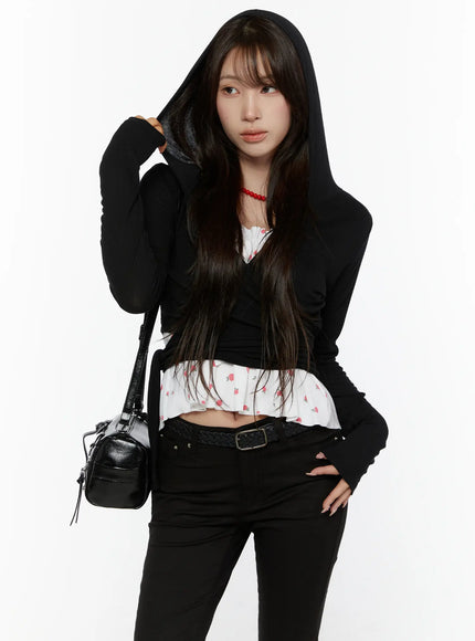 LEWKIN Hooded Wrap Crop Cardigan CL507 Black S/M front shot on model wearing hood up, adjusting hood with hand, styled with floral ruffle inner top and black jeans