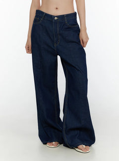LEWKIN Jael Dark Washed Wide Leg Jeans CL520 Dark blue front close-up on model showing low-rise waistband, silver button, yellow topstitching, and wide-leg denim silhouette
