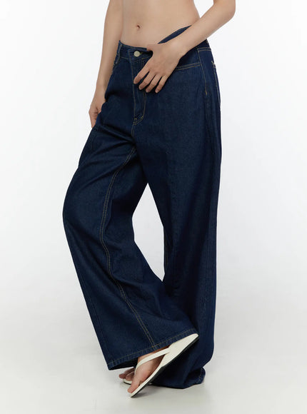 Jael Dark Washed Wide Leg Jeans CL520 Dark blue side view on model with hand resting on hip, showing low-rise fit and voluminous wide-leg denim silhouette with white sandals