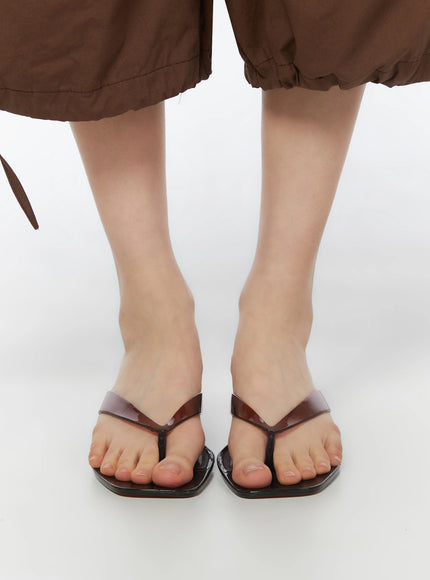 Jelly Flip-Flop Sandals IU525 Brown front close-up shot on model showing square toe thong straps and glossy patent finish from below