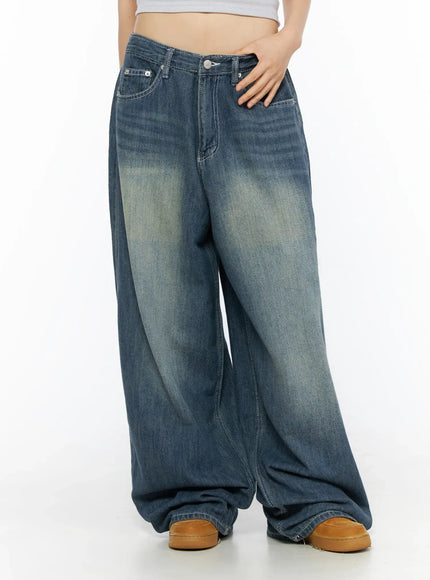 Jesse Vintage Wash Wide Leg Jeans CU530 Blue front lower-body view on model, low-rise waist with hand on hip, wide leg draped over tan sneakers