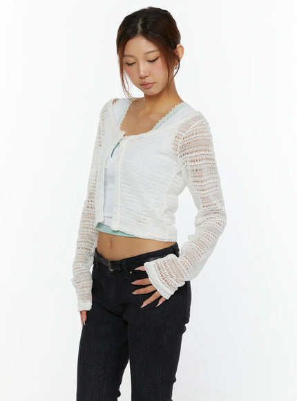 Knit Crop Cardigan CL515 White angled front shot on model looking down with hand on hip showing cropped length and open-knit texture
