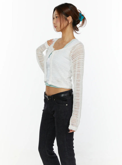Knit Crop Cardigan CL515 White side shot on model with hand on shoulder showing sheer open-knit sleeve and scallop neckline detail