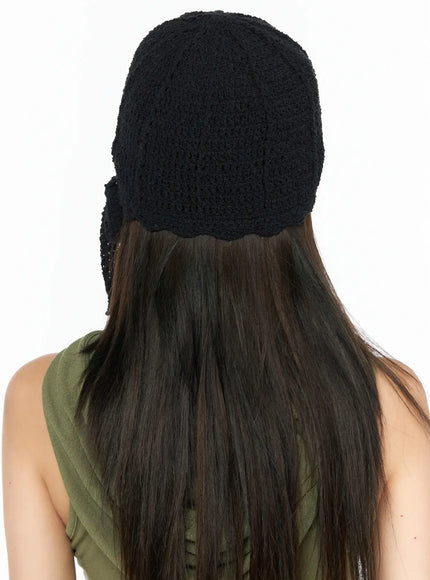 Knit Ribbon Beanie CL517 Black back view on model in green tank top, displaying full crochet texture, scalloped hem edge, and side bow tie detail