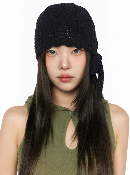 Knit Ribbon Beanie CL517 Black front portrait on model wearing green tank top, cap pulled low over brows, scalloped brim and side ribbon tie visible