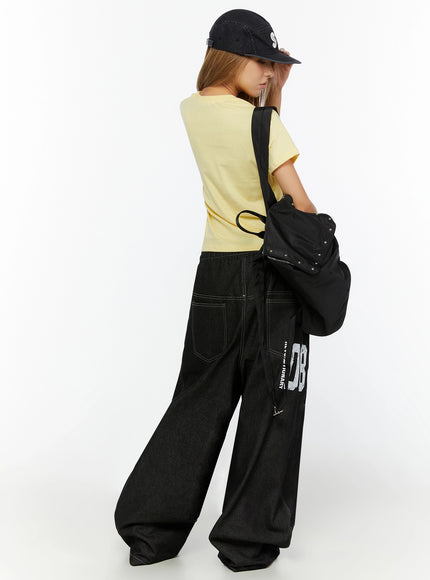 Kris Back Graphic Baggy Jeans IL524 Black back view on model styled with yellow graphic tee cap and crossbody bag showing back patch pockets and REVOLUTIONARY 08 print