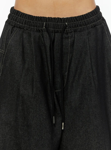 Kris Back Graphic Baggy Jeans IL524 Black close-up detail of elastic waistband with black drawstring and metal aglets and contrast white topstitching on denim