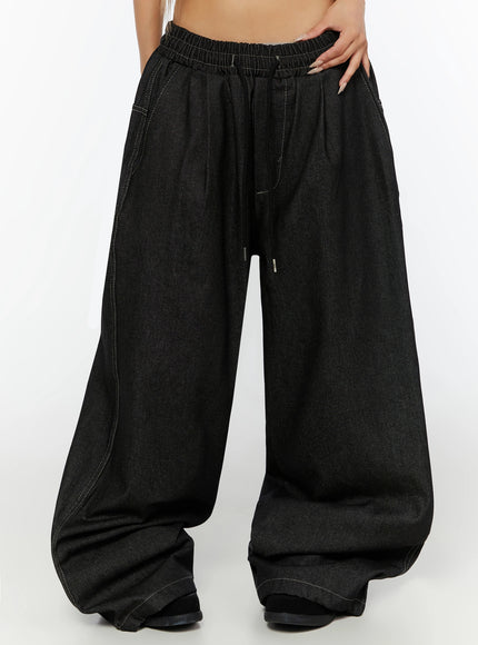 LEWKIN Kris Back Graphic Baggy Jeans IL524 Black front crop shot on model wearing M/L showing elastic drawstring waistband and ultra-wide leg denim silhouette