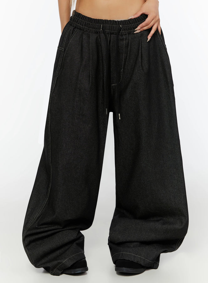 LEWKIN Kris Back Graphic Baggy Jeans IL524 Black front crop shot on model wearing M/L showing elastic drawstring waistband and ultra-wide leg denim silhouette