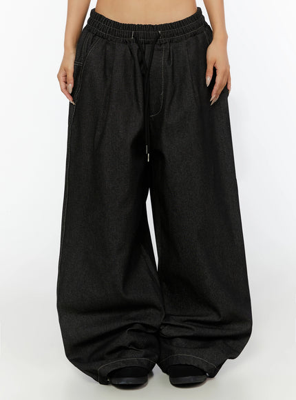 Kris Back Graphic Baggy Jeans IL524 Black front waist-down shot on model showing pleated wide-leg denim with elastic waist drawstring and pooling hem