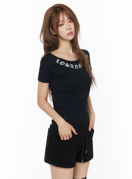 LA Graphic Round Neck Crop Top IL502 Black model side front shot, fitted ribbed crop tee with old English lettering, styled with black shorts