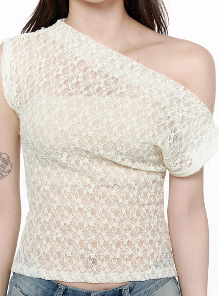 Lace Asymmetrical Off-Shoulder Top IL506 Light beige close-up front detail shot on model showing floral lace texture diagonal neckline and semi-sheer fabric