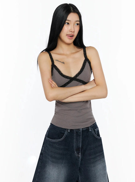 Lace Contrast Cami Top IL509 gray front shot on model with arms crossed showing black lace X-strap trim paired with wide-leg jeans