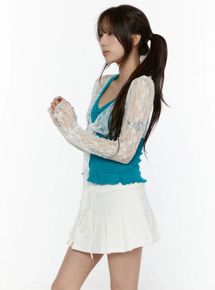 Lace Front-Tie Bolero CL507 White side shot on model with arms crossed, showing sheer lace sleeves and teal inner top with ruffled hem