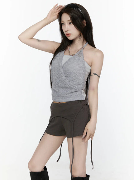 Lace Halter-Neck Top IL522 Gray three-quarter front shot model hand shielding forehead wearing gray lace wrap halter top with dark shorts and black boots chain necklace