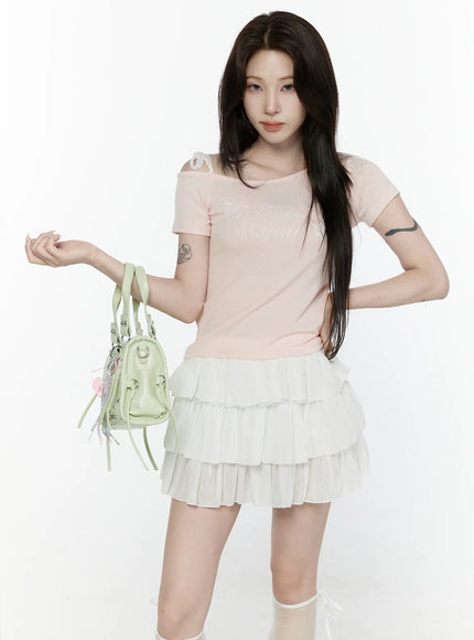 Lace Off-Shoulder Top IL521 Pink front shot on model holding green bag at waist level with asymmetric off-shoulder lace strap detail