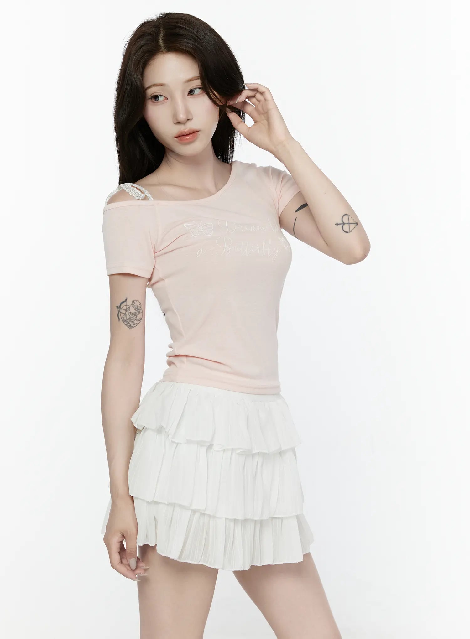 Lace Off-Shoulder Top IL521 Pink three-quarter front shot on model touching hair showing asymmetric neckline and butterfly script graphic print