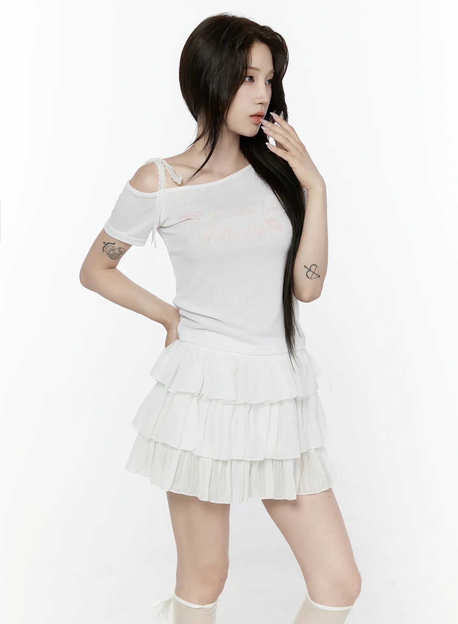Lace Off-Shoulder Top IL521 White three-quarter side shot on model hand near face showing off-shoulder lace strap and butterfly script on sheer ribbed knit
