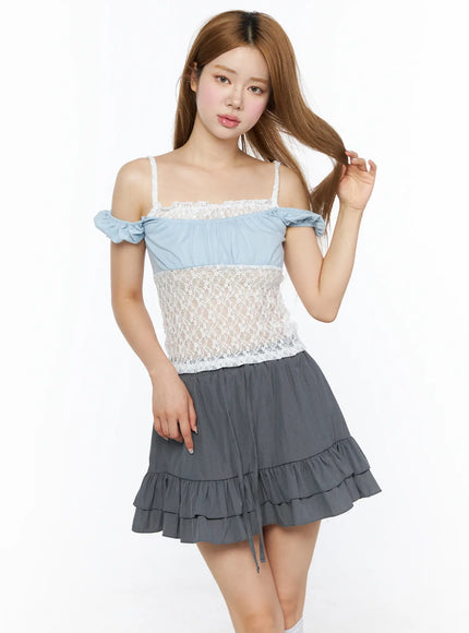 Lace Panel Cami Top CL501 Light blue front shot on model touching hair, three-quarter pose showing lace panel construction and gray ruffle mini skirt