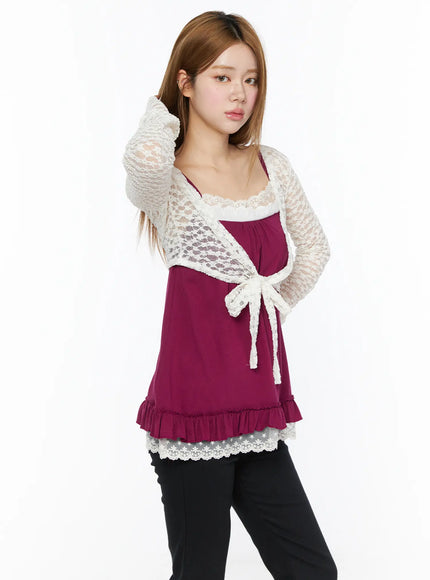 Lace Sheer Crop Cardigan CL502 White three-quarter front shot on model touching hair, lace tie bow detail visible over magenta cami with black pants