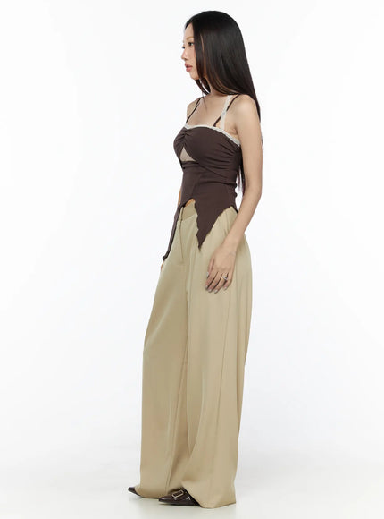 Lace Trim Asymmetric Cami CL524 Brown side shot on model showing cutout waist asymmetric hem and ruched chest detail with beige wide-leg trousers
