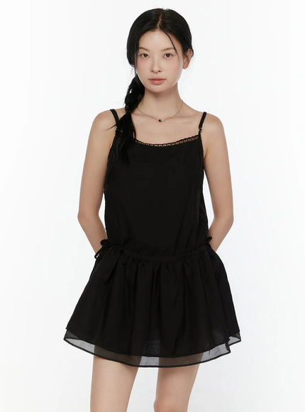 Lace Trim Cami Top CL520 Black front view on model showing spaghetti straps lace neckline trim drawstring waist and double-layer sheer peplum hem worn as mini dress