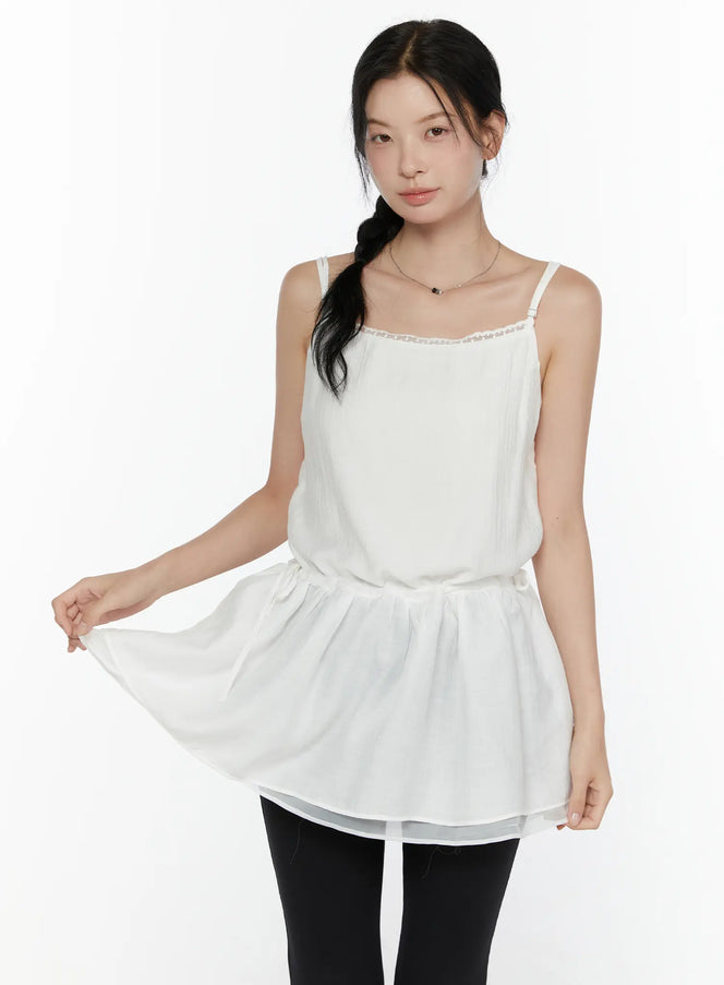 LEWKIN Lace Trim Cami Top CL520 White S/M front view on model lifting hem showing flowy layered peplum silhouette with lace neckline trim paired with black leggings