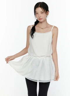 LEWKIN Lace Trim Cami Top CL520 White S/M front view on model lifting hem showing flowy layered peplum silhouette with lace neckline trim paired with black leggings