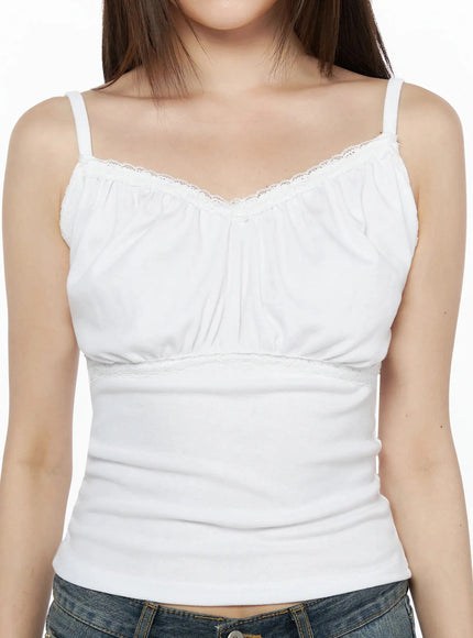 Lace Trim Cami Top IL523 White close-up front detail shot on model highlighting lace V-neckline trim, gathered bust fabric, empire waist lace band, and ribbed lower panel