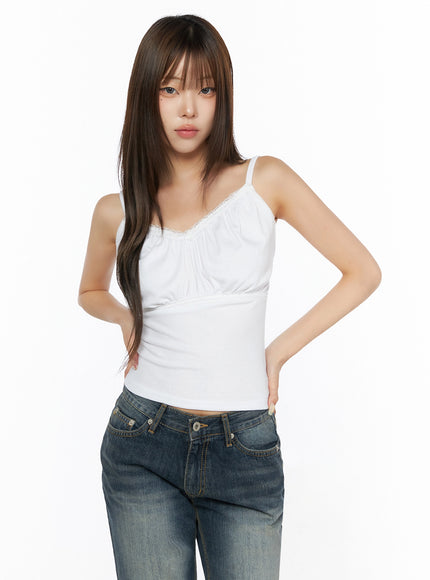 Lace Trim Cami Top IL523 White front shot on model with hands on hips, showcasing lace neckline, gathered chest, empire waist seam, thin spaghetti straps