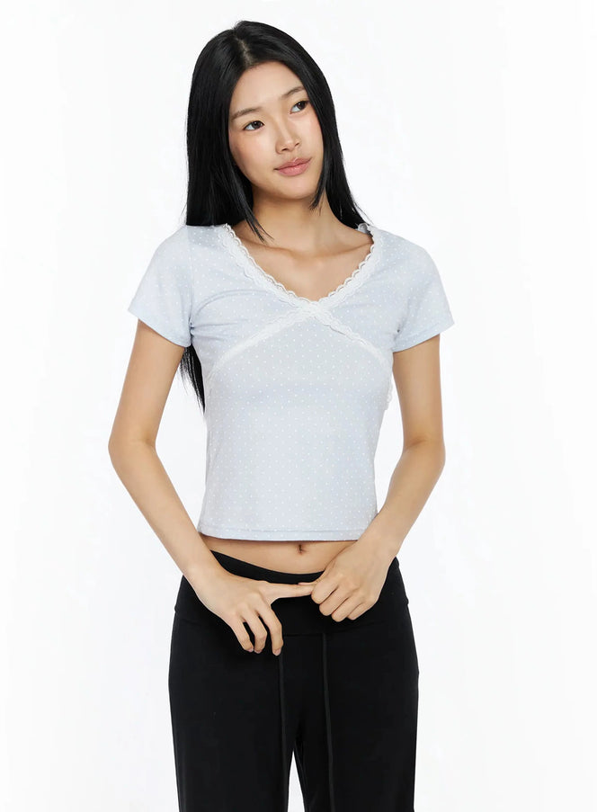Lace Trim Polka Dot Top IL509 light blue front shot on model with lace V-neckline and cross seam detail, paired with black pants