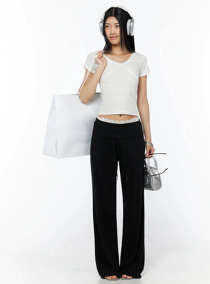 Lace Trim Polka Dot Top IL509 White full-length front shot on model holding shopping bag and silver mini bag with headphones