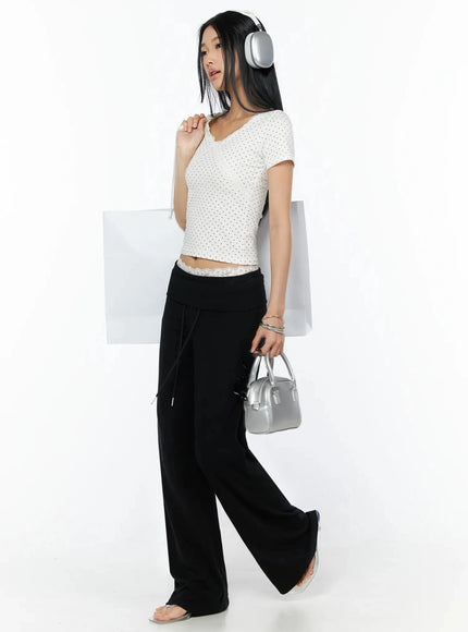 Lace Trim Polka Dot Top IL509 White side shot on model carrying shopping bag and silver handbag with headphones, lace hem visible