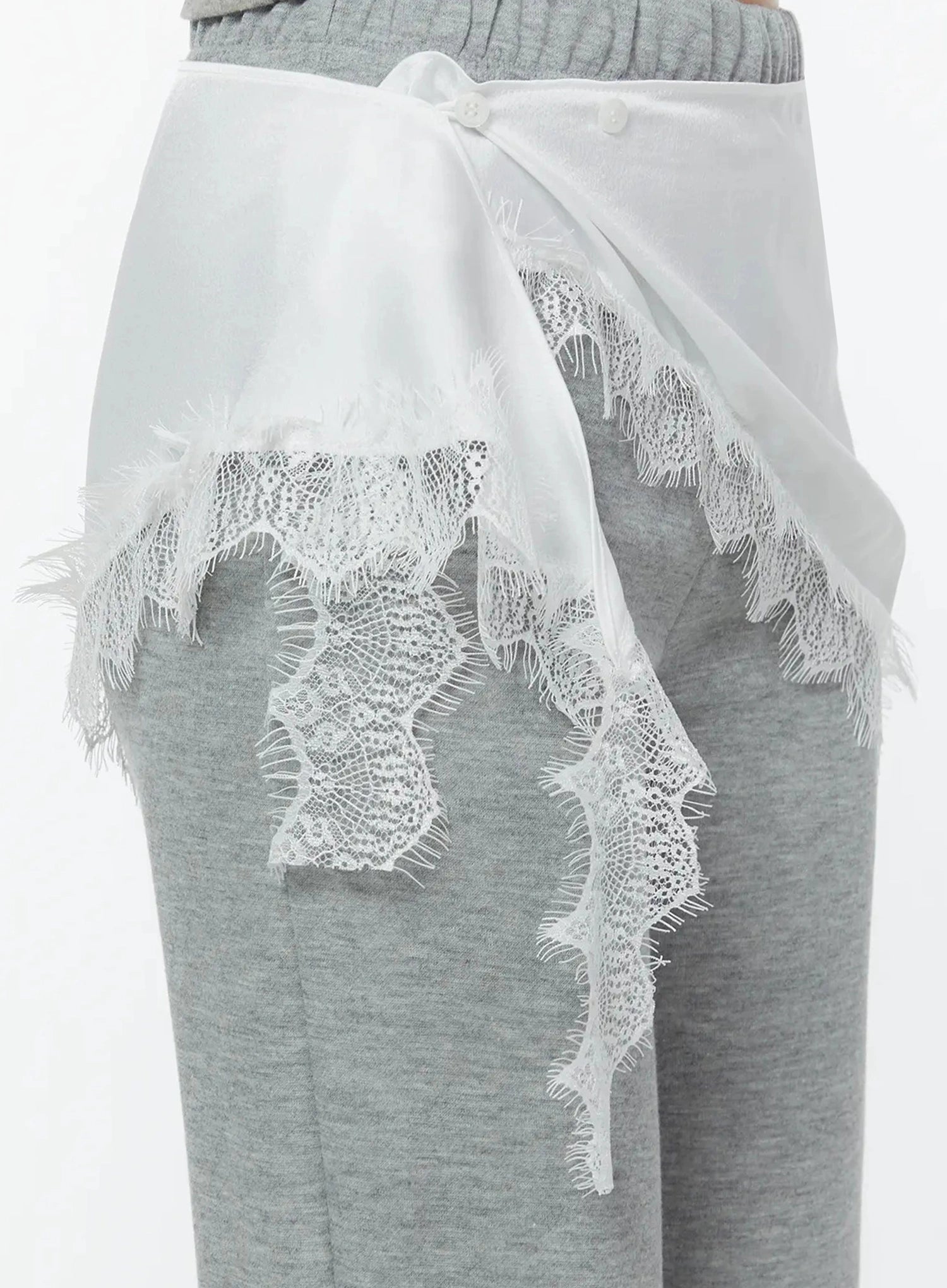 Lace Trim Satin Layering Skirt IU524 White side close-up detail on model showing back panel button closure and cascading lace trim tail against gray flare pants