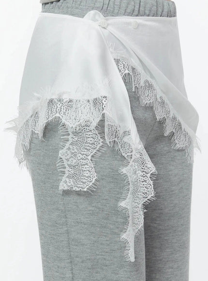 Lace Trim Satin Layering Skirt IU524 White side close-up detail on model showing back panel button closure and cascading lace trim tail against gray flare pants