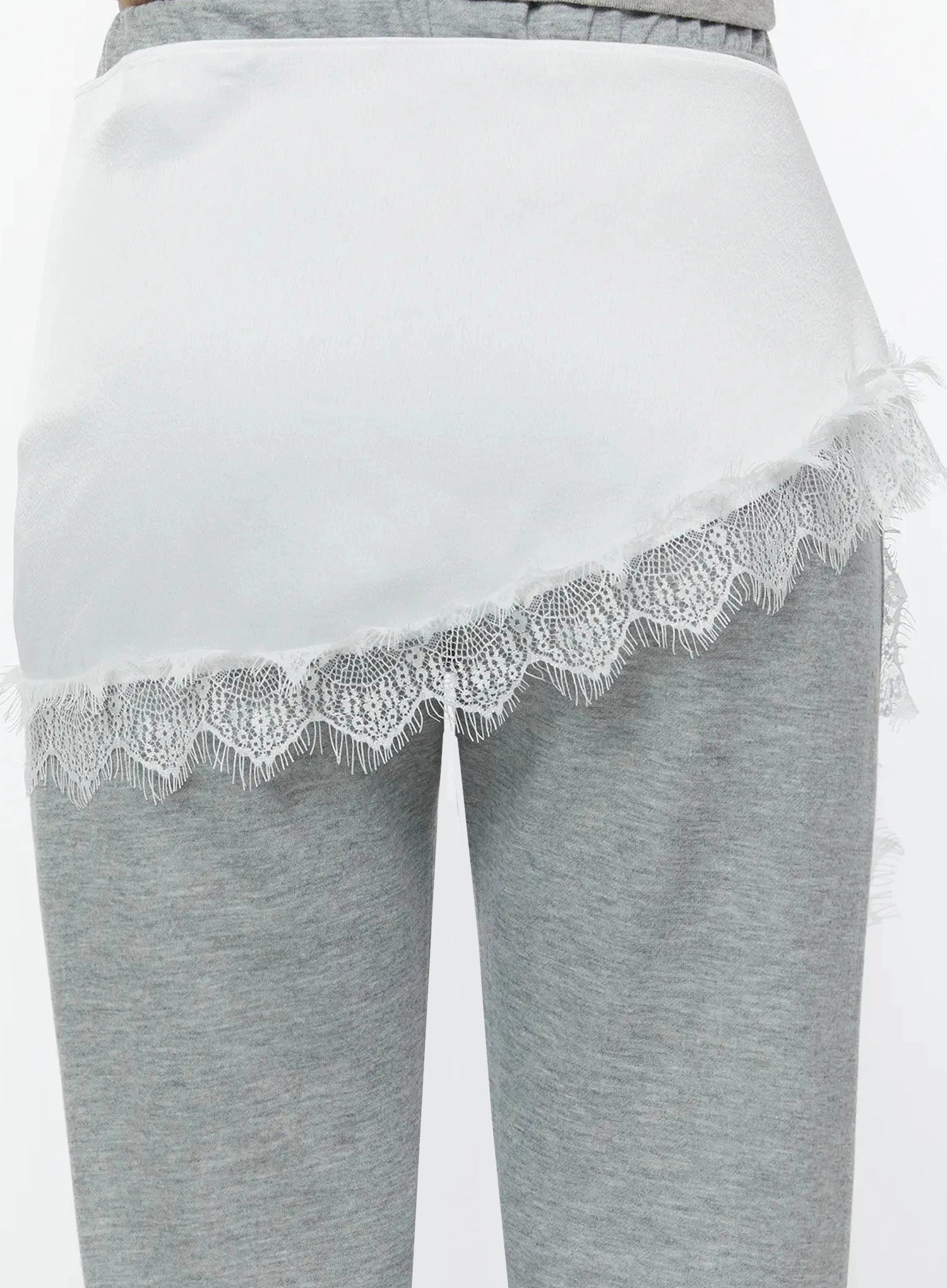 Lace Trim Satin Layering Skirt IU524 White back close-up detail on model revealing smooth satin fabric panel with scalloped lace trim hem over gray marl pants