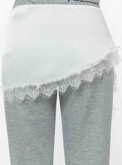Lace Trim Satin Layering Skirt IU524 White back close-up detail on model revealing smooth satin fabric panel with scalloped lace trim hem over gray marl pants