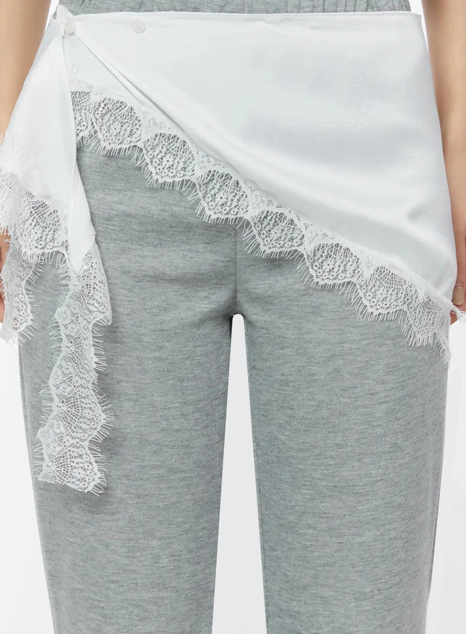 LEWKIN Lace Trim Satin Layering Skirt IU524 White close-up detail on model showing asymmetric wrap silhouette with scalloped lace trim edging over gray flare pants