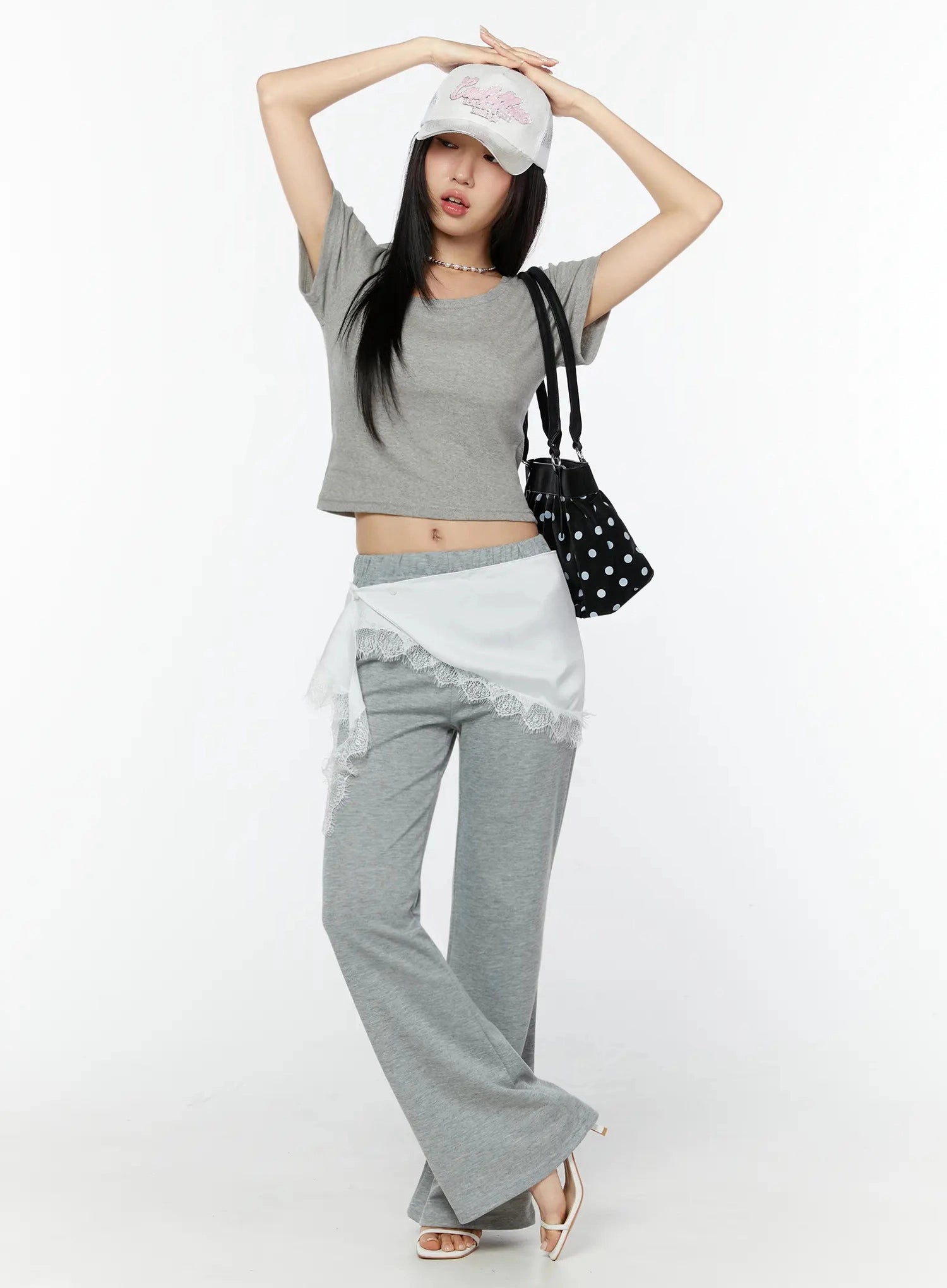 Lace Trim Satin Layering Skirt IU524 White front full-body shot on model arms raised wearing cap and polka-dot bag styled with gray crop top and gray wide-leg pants